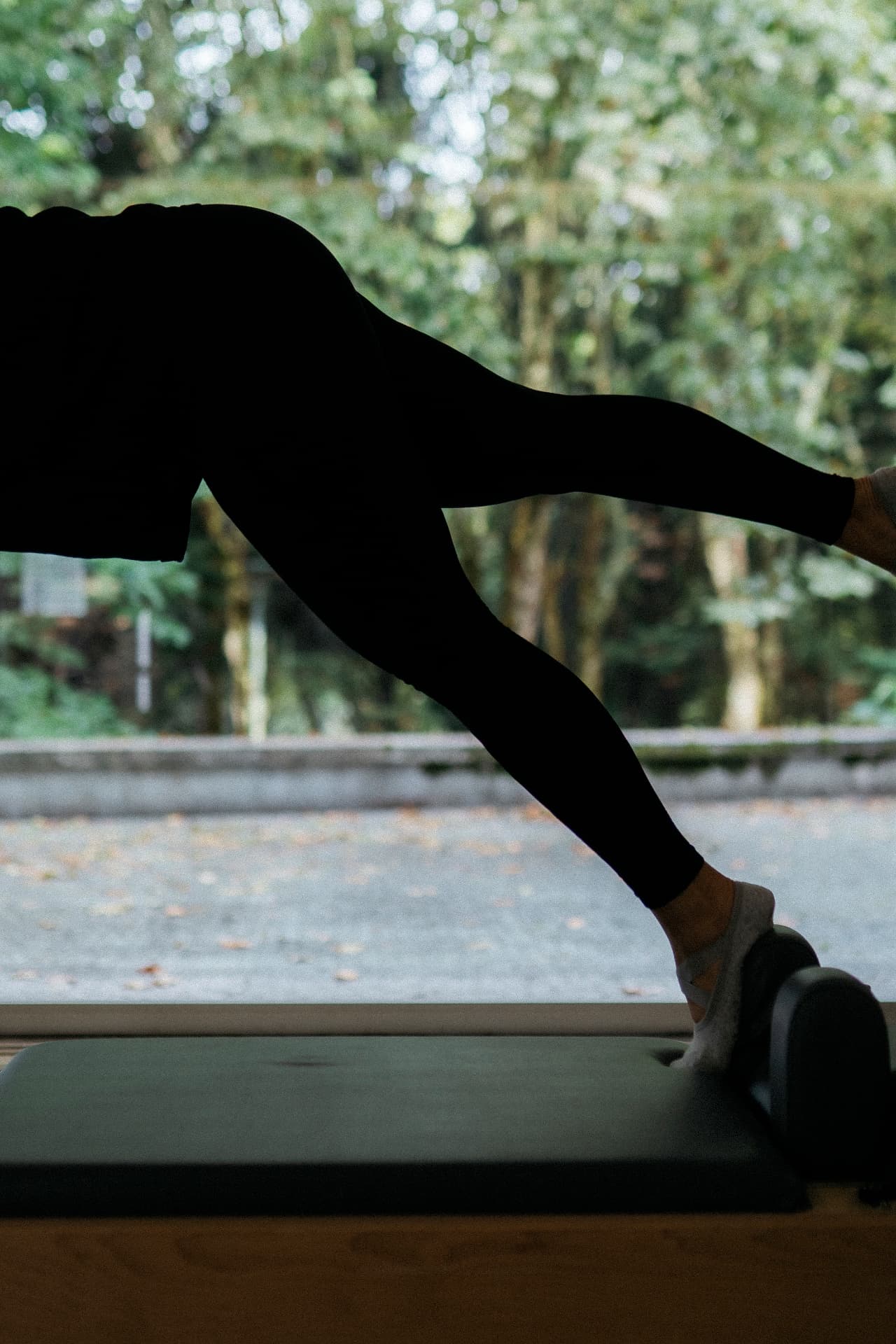 Exercício no Reformer em pé, com o parque visível ao fundo