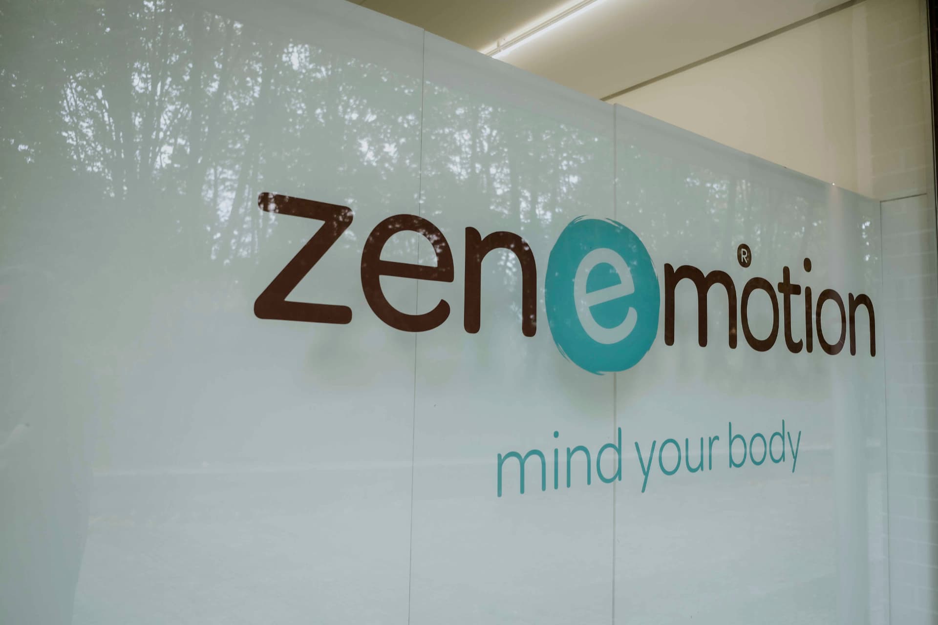 Logotipo zenemotion® na parede de vidro do estúdio