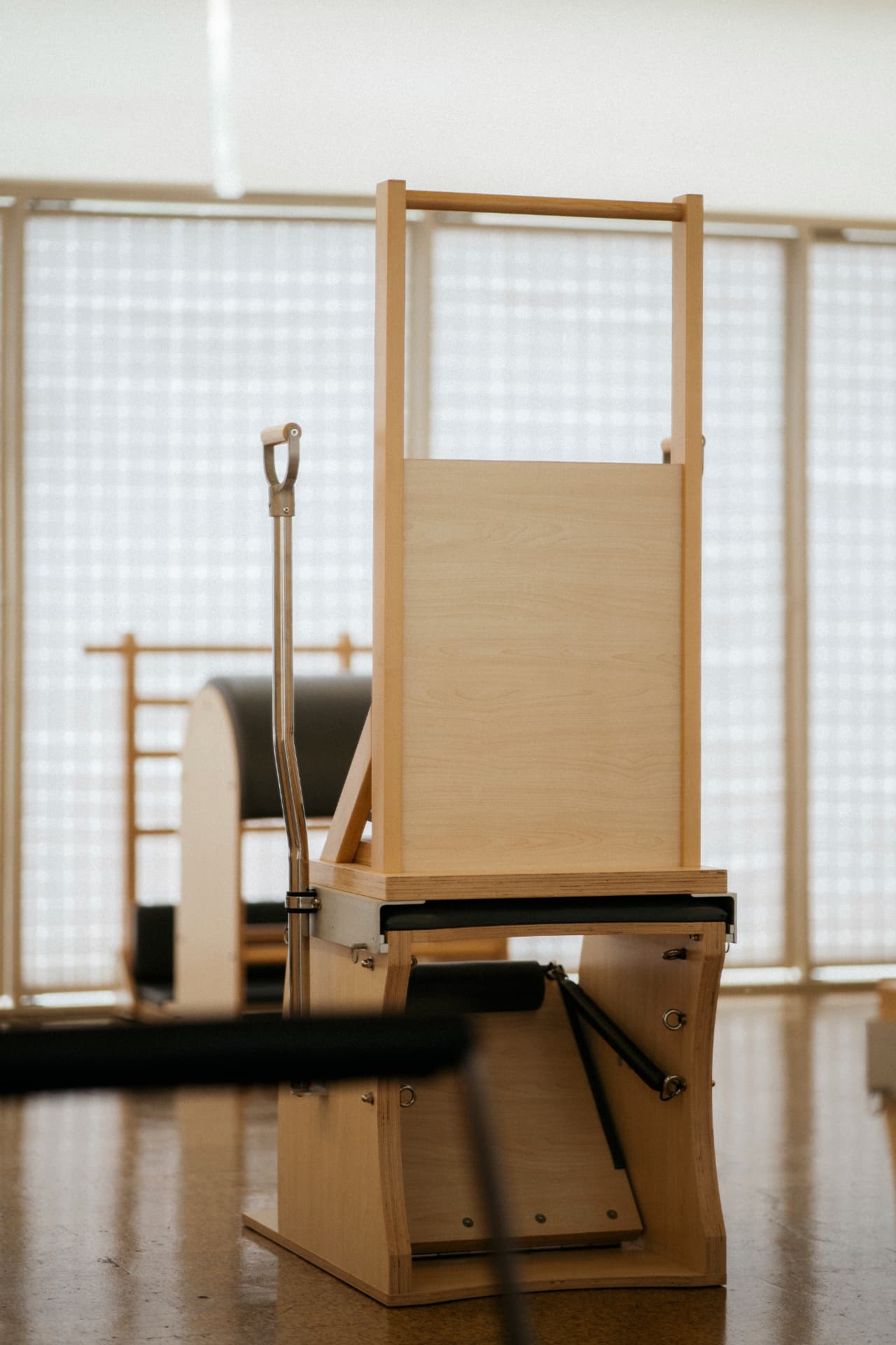 Chair de Pilates em madeira, com equipamento ao fundo